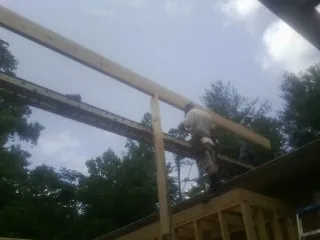 Carpenter setting a ridge beam over a new addition frame — Ice Dam Removal by Roofing Brothers in Alexis