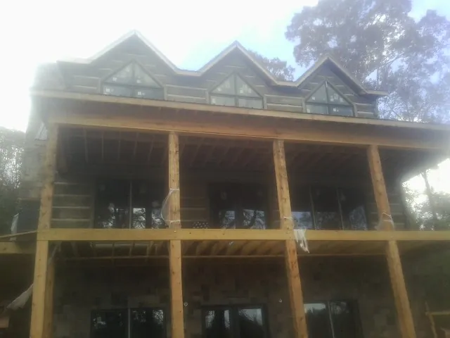 Dormers and porch framing on a large log home under construction — Roof Coating work by our crew in Alexis