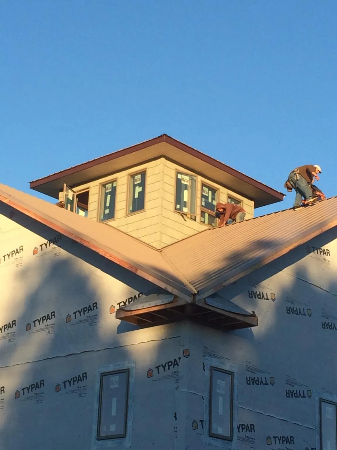 Roofers working around a rooftop cupola on a new metal roof at sunset — Roof Waterproofing in Alexis by Roofing Brothers